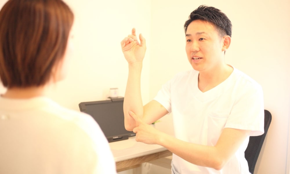 肘と手の筋膜の繋がりの説明をする入間ひばり整骨院の院長先生